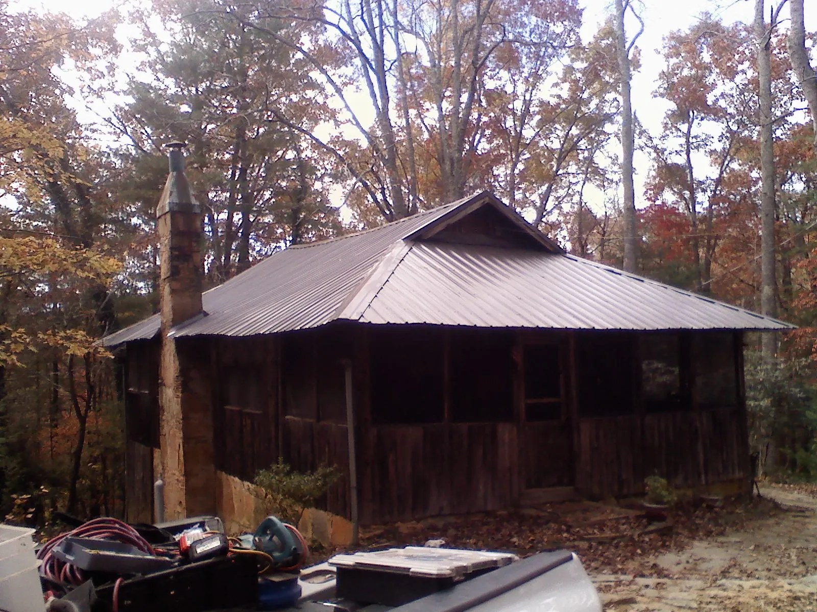 Brown metal hip roof on an old cabin with a stone chimney in Burlington
